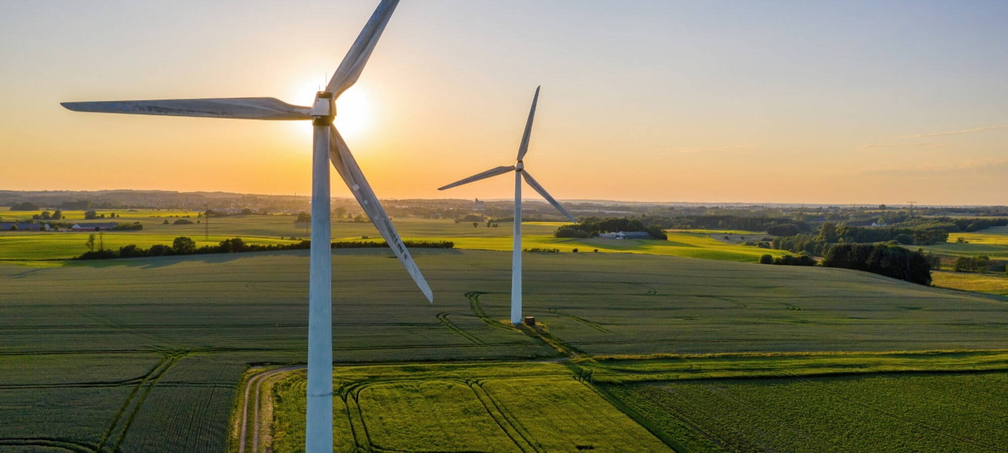 pretty onshore wind farm with sunset background and lots of green fields ersg