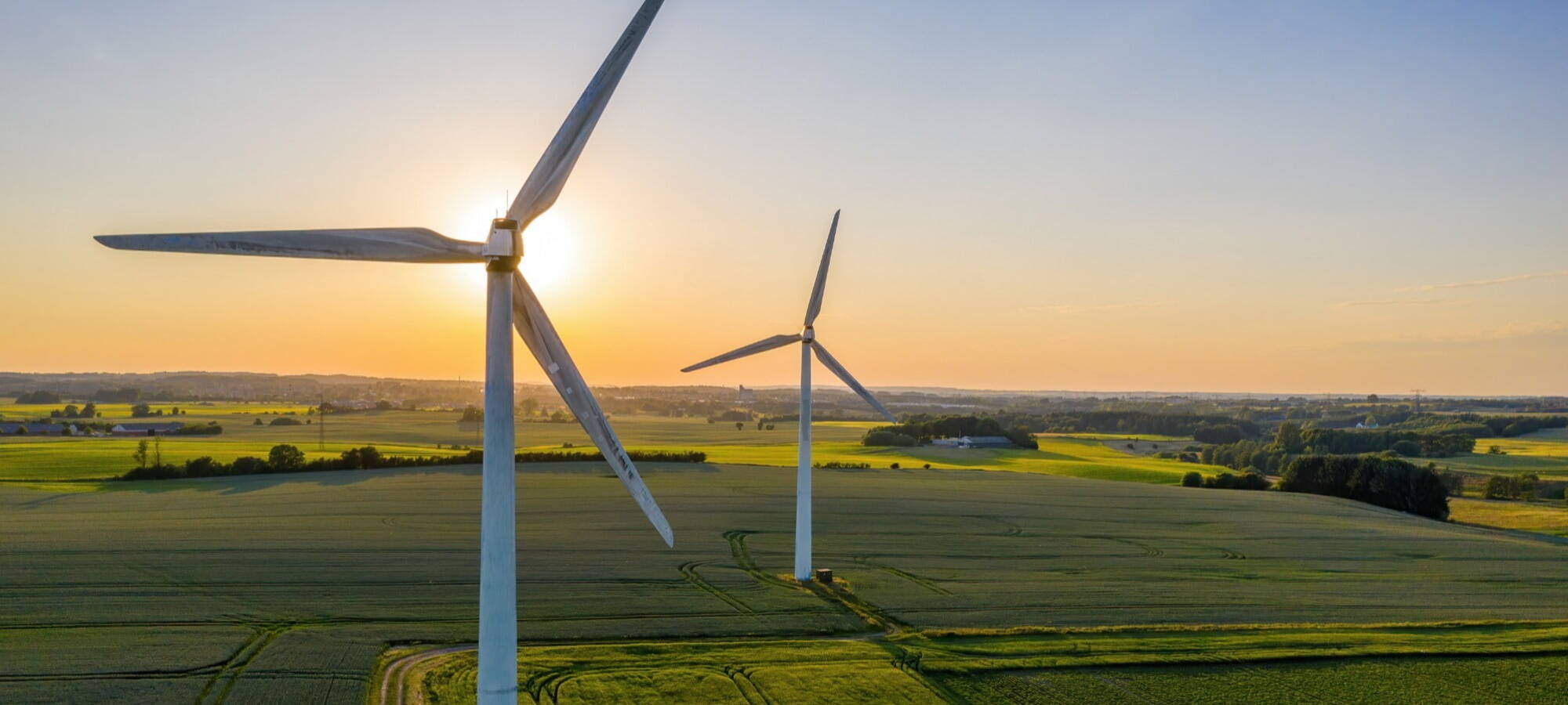 pretty onshore wind farm with sunset background and lots of green fields ersg